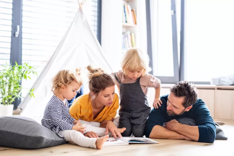 Couple reading a book to two young children
