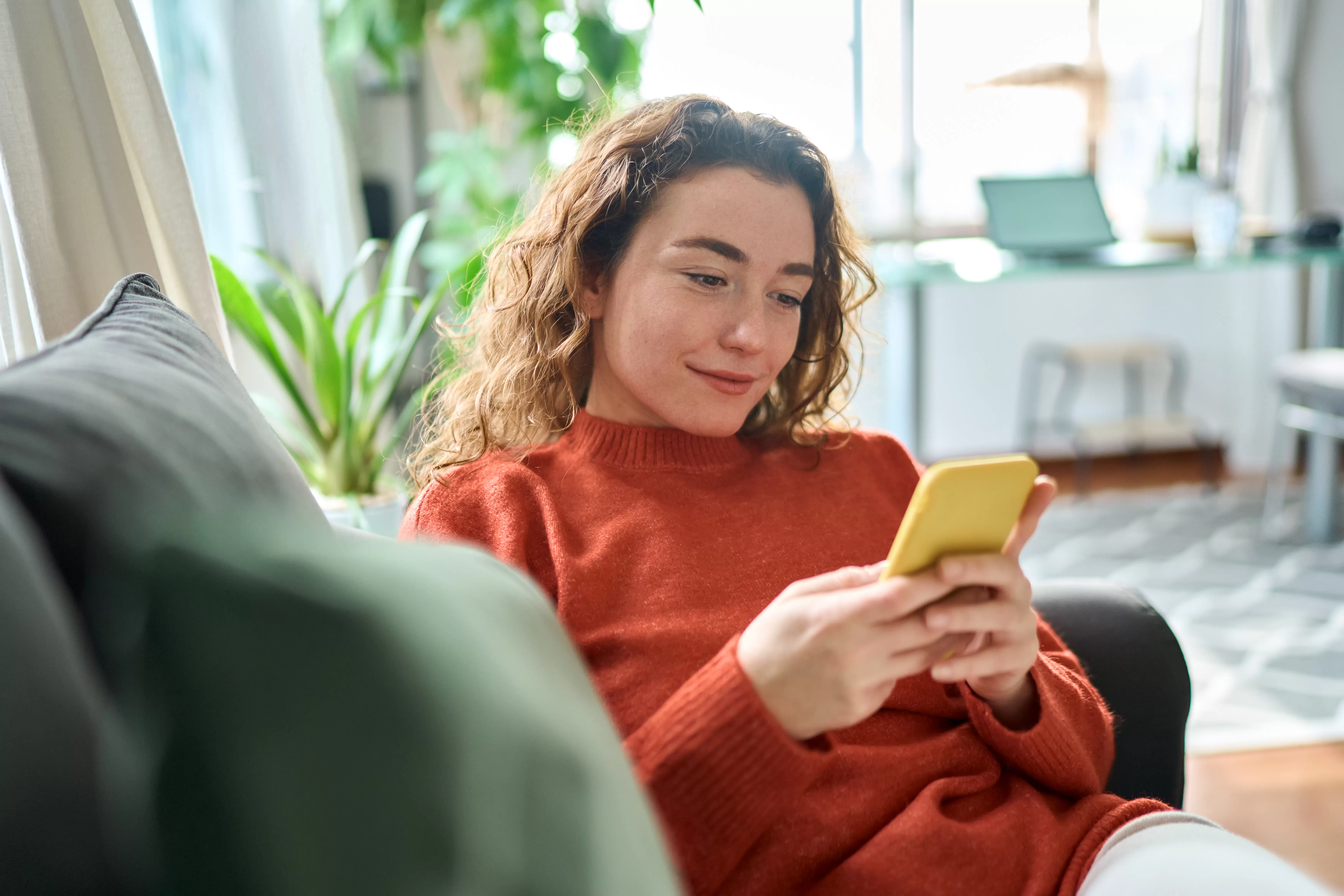 Woman sitting on her couch and looking at her phone