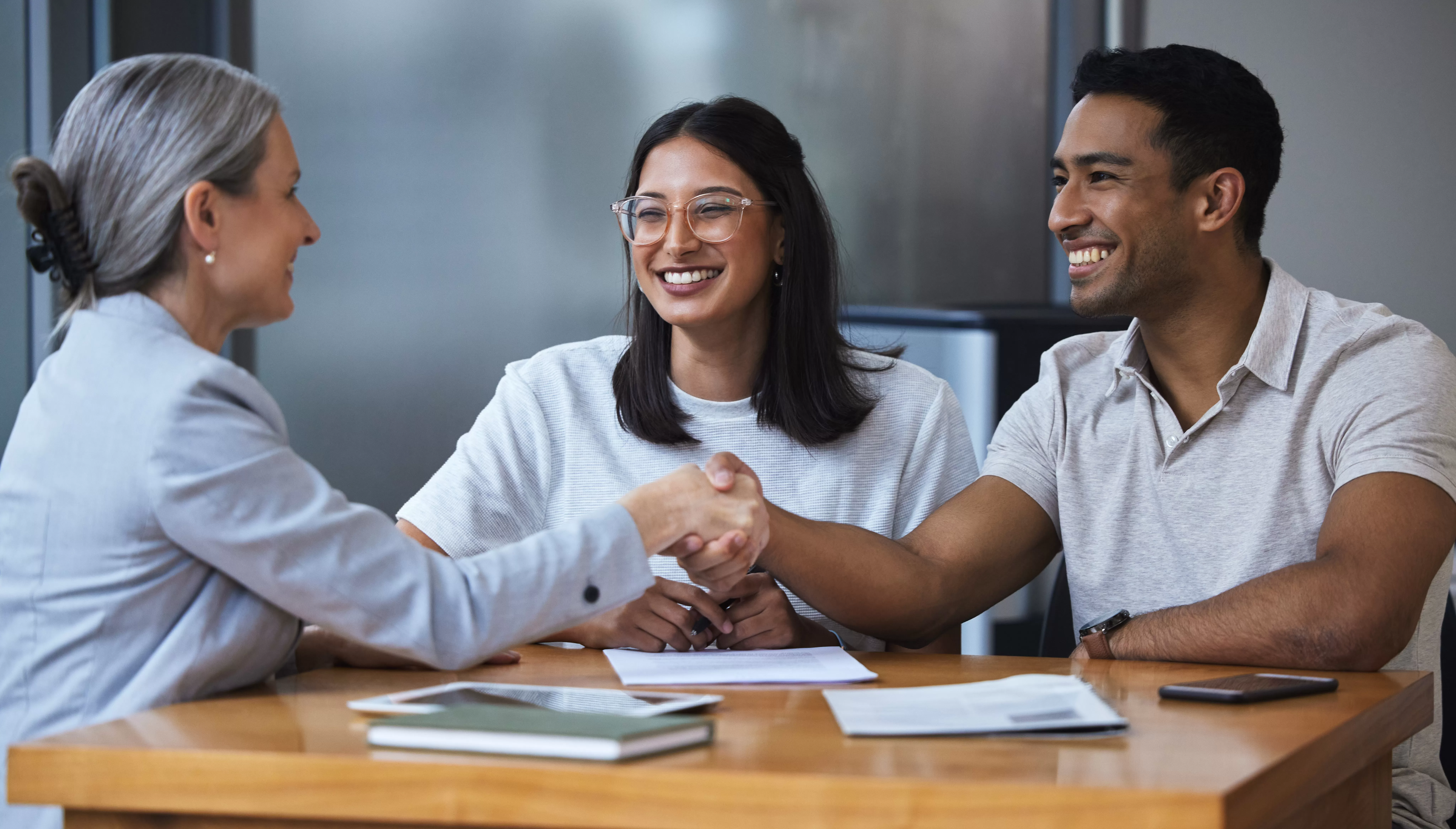 A young man and wife shaking the hands of a Members Heritage CU banker after opening a credit union Traditional IRA.